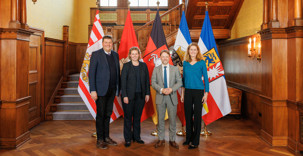 Dr. Andreas Dressel, Wiebke Stuhrberg, Gerald Heere und Dr. Silke Schneider stehend vor den Flaggen der Norddeutschen Bundesländer